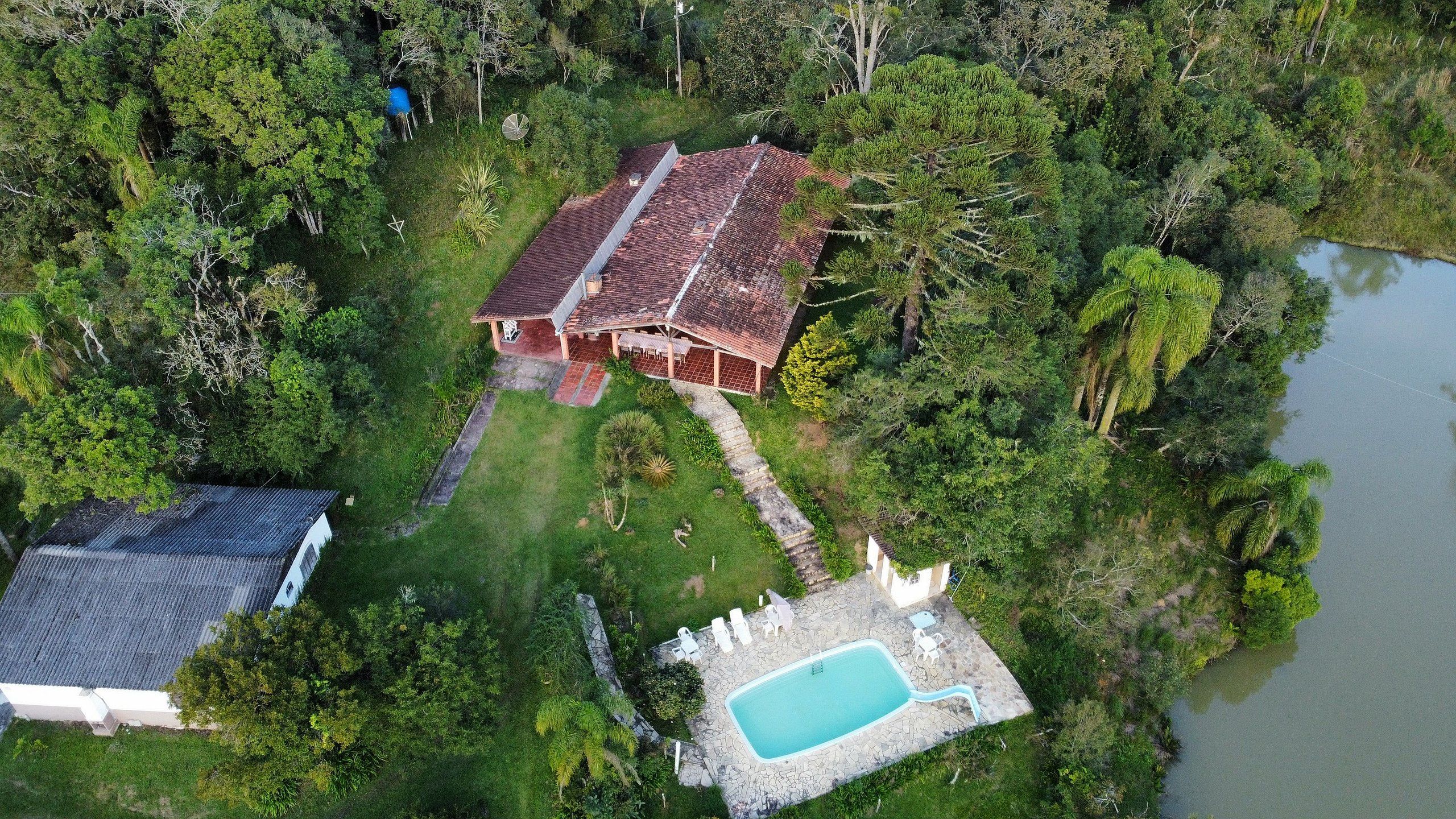 Vista aérea de uma propriedade com um edifício principal, uma piscina e uma construção menor.