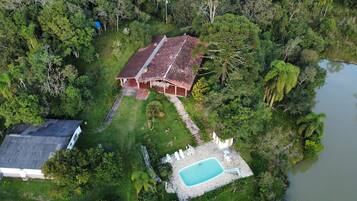 Vista aérea de uma propriedade com um edifício principal, uma piscina e uma construção menor.