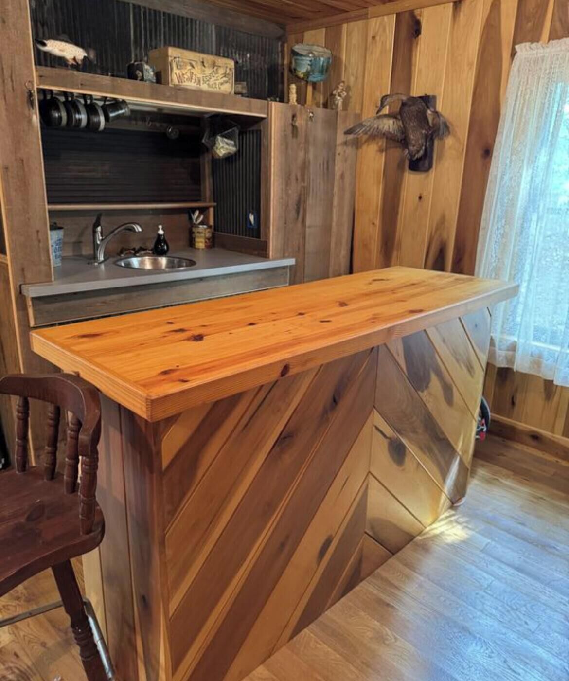 Una cucina in legno con isola integrata, un lavello e un arredamento rustico.