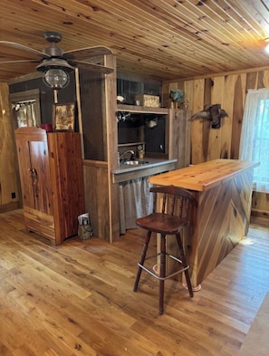 Una cocina rústica con paredes de madera, una barra de madera y un ventilador de techo.