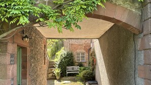 A stone building with a covered walkway, a green door, and a bench in the background. - Cottage in Heart of the Eden Valley (Penrith)