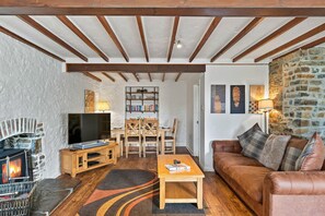 Ein gemütliches Wohnzimmer mit Kamin, Fernseher, Holzmöbeln und einer Steinwand.