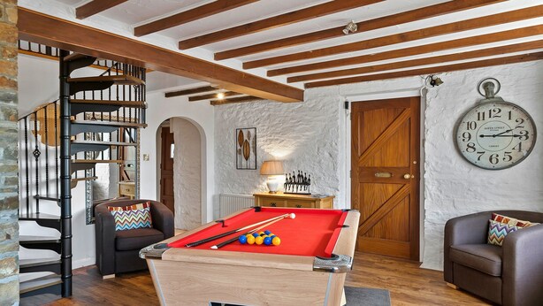 Um quarto acolhedor com mesa de bilhar, relógio e estante de livros.