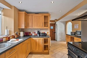Una cocina con armarios de madera, encimera negra, tostadora, hervidor y microondas.