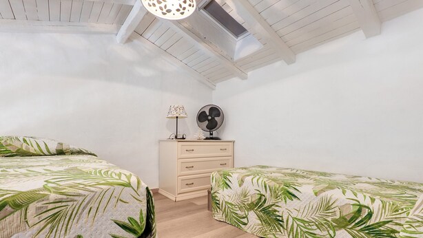 Ein Schlafzimmer mit zwei Betten, einem Schminktisch, einer Lampe und einem Ventilator.