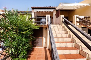 A staircase leading to a building entrance with a tiled floor and a wooden handrail. - Apartment 'Marea  - By and Service' (Golfo Aranci)