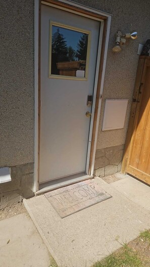 Una puerta con ventana, un buzón y un felpudo.