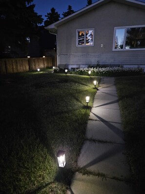 A residential property at night with a well-lit pathway and a house number 20. - Come Stay at "Night at the Movies" with all the comforts of home! (Calgary)