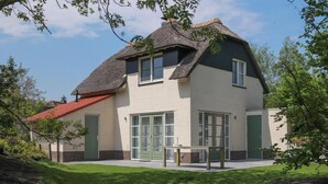 A two-story house with a thatched roof, large windows, and a well-maintained lawn. - Makkum Villa With Whirlpool for 6 (Makkum)