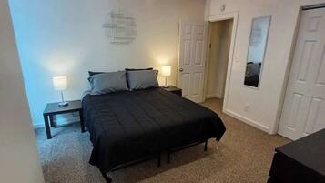 Ein Schlafzimmer mit einem Bett, Nachttischen, einem Spiegel und einer Tür.