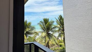 A balcony with a view of palm trees and the ocean.