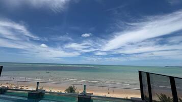 A view from a balcony overlooking a beach with a clear sky.