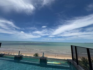 Vista desde un balcón con vista a una playa y cielo despejado.