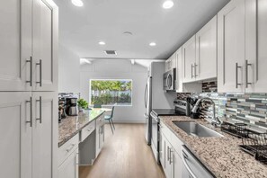 Una cocina moderna con armarios blancos, encimeras de granito y vistas a zonas verdes.