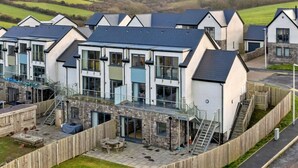 A modern residential complex with multiple houses, each featuring a balcony and a stone facade. - Stunning Broad Haven Beach House (Haverfordwest)