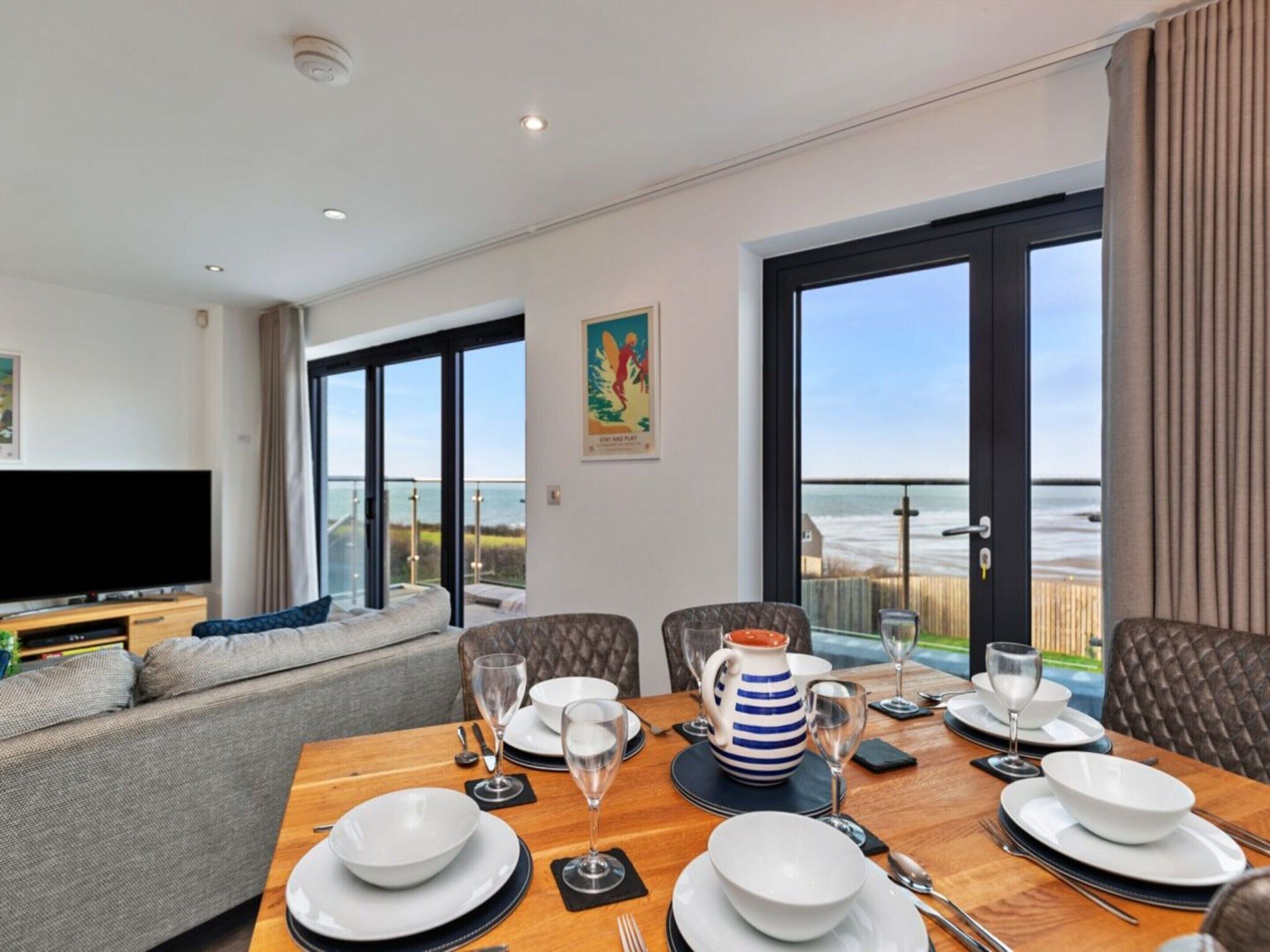 A dining area with a table set for four, a television, and a sofa.