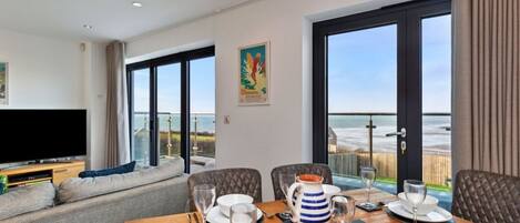 A dining area with a table set for four, a television, and a sofa.