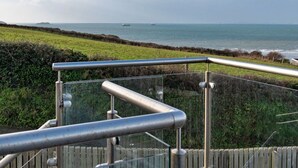 A coastal view with a metal railing, grassy fields, and the sea in the background. - Stunning Broad Haven Beach House (Haverfordwest)