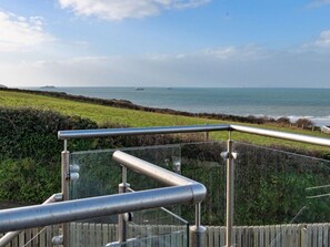 A coastal view with a metal railing, grassy fields, and the sea in the background. - Stunning Broad Haven Beach House (Haverfordwest)