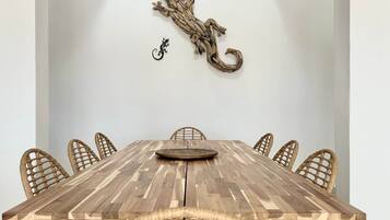 Ein Esstisch mit sechs Korbstühlen, einem Wanddekor und einer kleinen Skulptur.