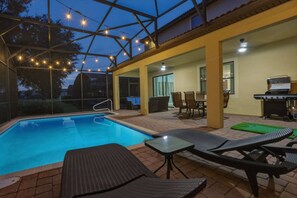 Zona de piscina exterior con sillas de descanso y una parrilla.