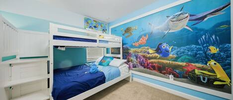 Un dormitorio infantil con literas, un mural de una escena submarina y una lámpara en el techo.