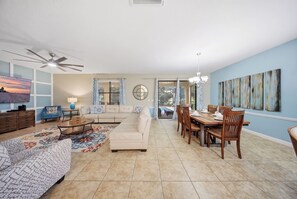 A spacious living area with a sofa, coffee table, and dining table set up. - Lola’s Oasis | 5BR Pool Home + Lazy River + Disney (Four Corners)