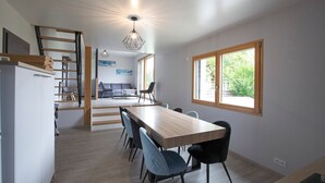 A modern kitchen with a dining area, wooden flooring, and a view through a window. - Bed and Breakfast 'Chambre La Grande Ourse' with Lake View, Shared Terrace and Wi-Fi (Grande-Rivière Château)