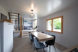 A modern kitchen with a dining area, wooden flooring, and a view through a window. - Bed and Breakfast 'Chambre La Grande Ourse' with Lake View, Shared Terrace and Wi-Fi (Grande-Rivière Château)