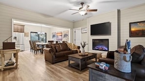 A living room with a fireplace, a television, and a dining area with a table and chairs. - Private Pool Spa, Sauna, Arcade & Views of Dollywood Fireworks (Pigeon Forge)