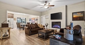 A living room with a fireplace, a television, and a dining area with a table and chairs. - Private Pool Spa, Sauna, Arcade & Views of Dollywood Fireworks (Pigeon Forge)