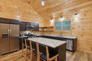 A modern kitchen with wooden walls, stainless steel appliances, and a central island with bar stools.