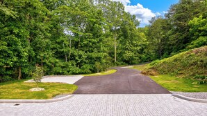 A paved pathway leading into a forested area with a road curving to the right. - Dollys Cabins 1010  - Walk to Dollywood! (Pigeon Forge)