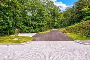 A paved pathway leading into a forested area with a road curving to the right. - Dollys Cabins 1010  - Walk to Dollywood! (Pigeon Forge)