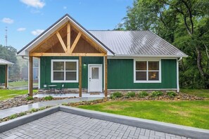 A green building with a covered porch and a paved walkway.