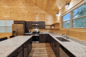 Una cocina moderna con paredes de madera, electrodomésticos de acero inoxidable, encimeras de granito y un ventanal grande.