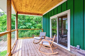 A wooden deck with two rocking chairs and a glass door leading to a green-painted room. - Dollys Cabin 1012 - Walk to Dollywood! (Pigeon Forge)