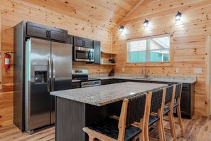 Eine moderne Küche mit einem Edelstahl-Kühlschrank, einer eingebauten Mikrowelle und einer Arbeitsplatte aus Granit.