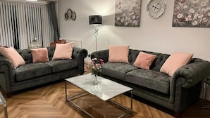 Ein Wohnzimmer mit zwei dunkelgrauen Sofas, einem Glastisch und einer Stehlampe.