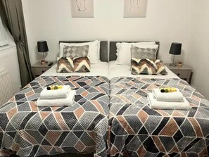A double bed with patterned bedding and two towels on each side. - House Sleeps 6 With Enclosed Garden (Birkenhead)