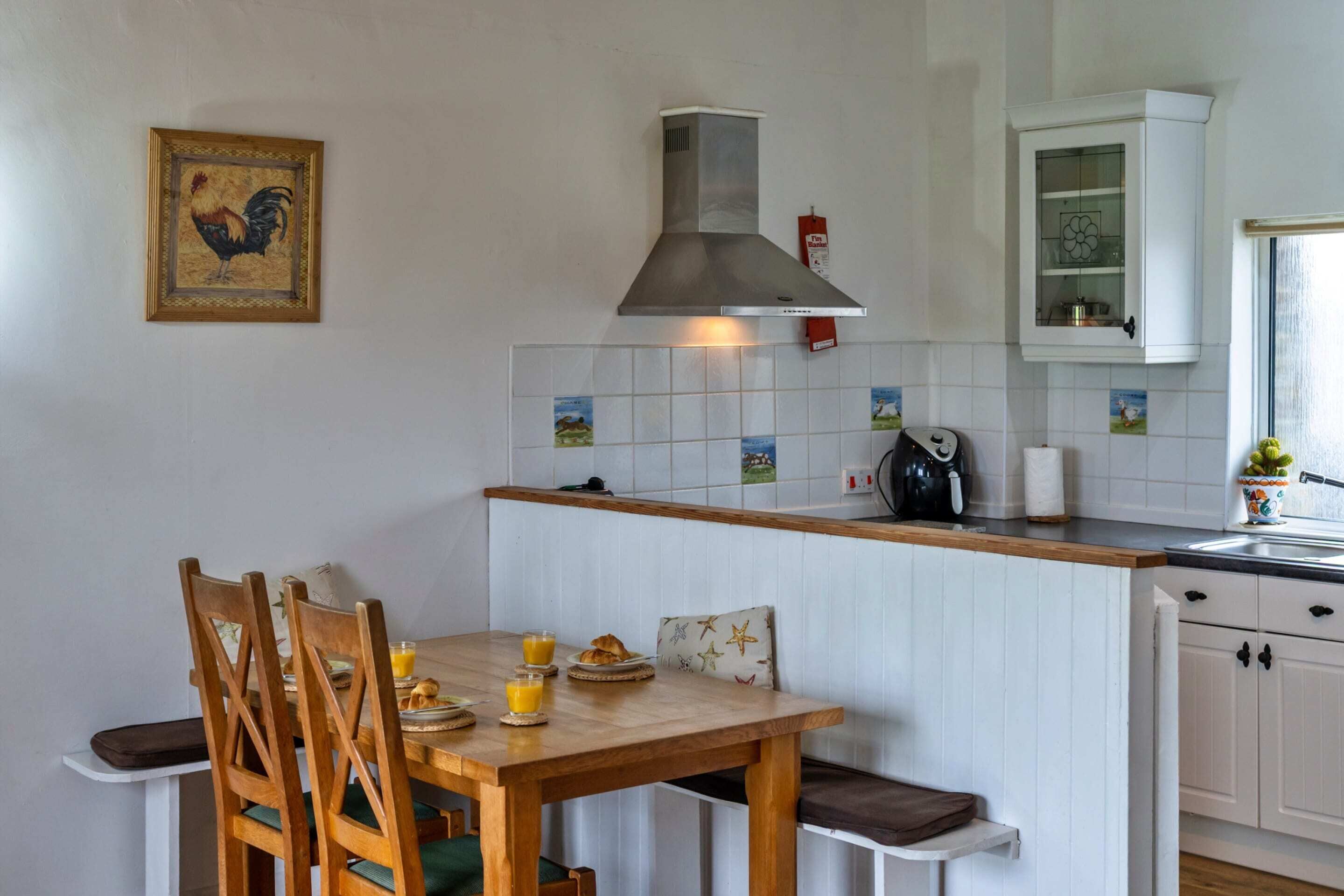 Una cocina con una mesa de madera, sillas, una estufa a gas, una cafetera y una ventana con vistas.
