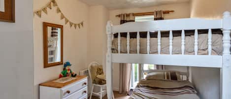 A bunk bed room with a dresser, a mirror, and a small chair.