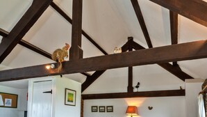A room with exposed wooden beams, a door, a framed picture, and a wall-mounted lamp.