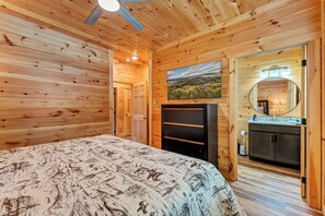 A wooden room with a bed, a dresser, a mirror, and a painting on the wall. - Dollys Cabins 1014 - Walk to Dollywood! (Pigeon)