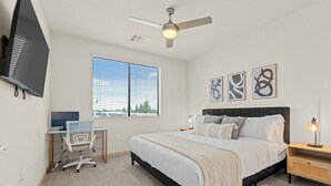 A bedroom with a bed, a desk, a chair, a ceiling fan, and artwork on the wall. - 2BR Tempe Oasis - King Beds, Pool, Gym, DT Tempe (Tempe)