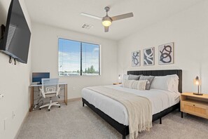 A bedroom with a bed, a desk, a chair, a ceiling fan, and artwork on the wall. - 2BR Tempe Oasis - King Beds, Pool, Gym, DT Tempe (Tempe)