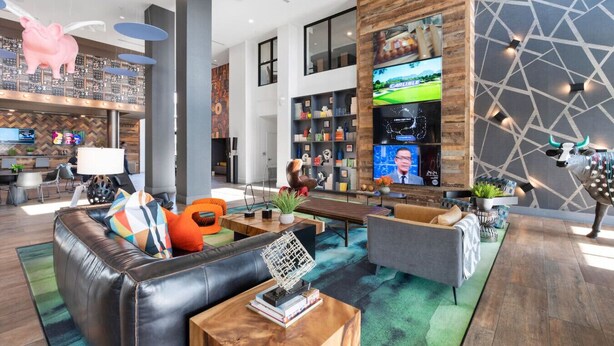 A modern hotel lobby with leather sofas, a coffee table, a TV, and a bull statue. - 2BR Tempe Oasis - King Beds, Pool, Gym, DT Tempe (Tempe)