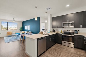 Una cocina moderna con armarios oscuros, electrodomésticos de acero inoxidable y una isla central.