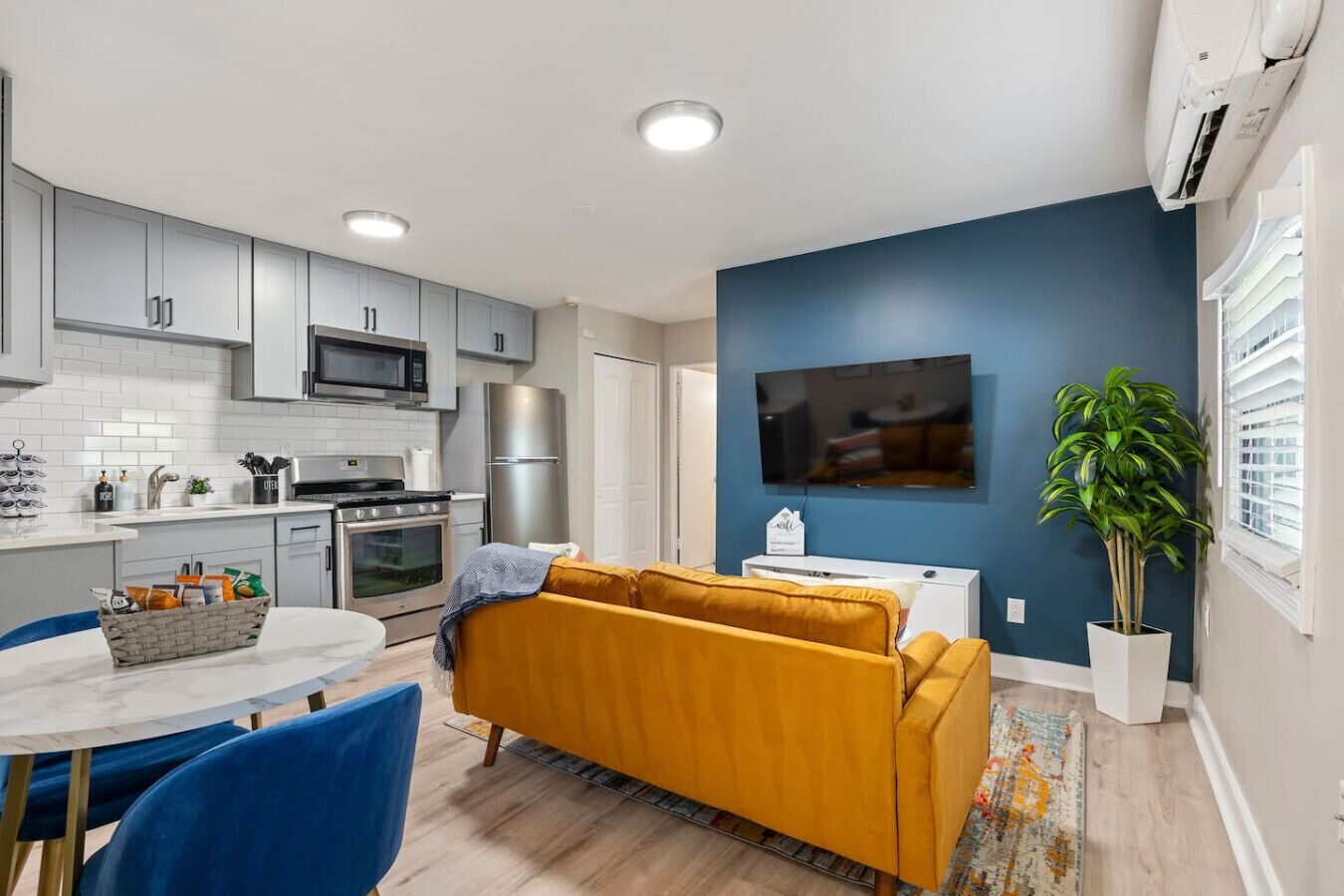 A modern kitchen with grey cabinets, a microwave, a refrigerator, and a dining area with a table and chairs.