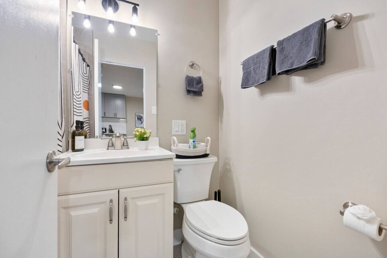 A bathroom with a white sink, mirror, and toilet. There are two towels on the wall.